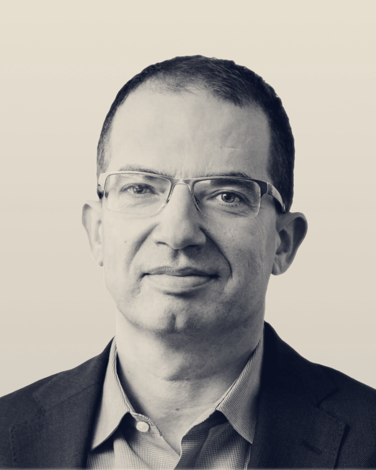 Stéphane Bancel, chief executive of Moderna. A cropped, duotone-treated version of the company's official leadership portrait: a man in his fifties in glasses and a dark jacket, looking at the camera.